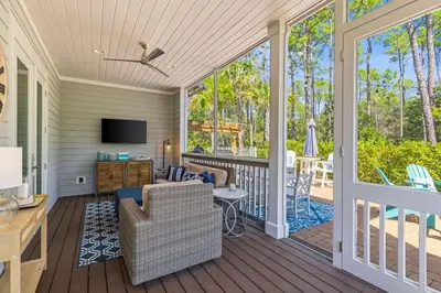 a screened in porch with a couch and a television at Nature and the Beach in Santa Rosa Beach