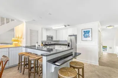 a kitchen with white cabinets and bar stools at Blue Tide 6B in Inlet Beach