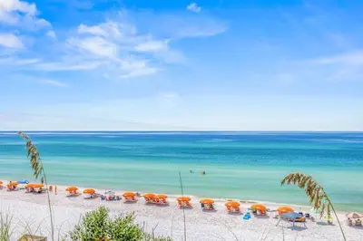 a beach with umbrellas and chairs and the ocean at Blue Tide 6B in Inlet Beach