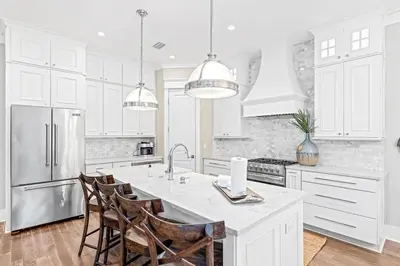 a kitchen with white cabinets and a kitchen island with chairs at A Shore Bet in Santa Rosa Beach