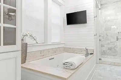a white bathroom with a tub and a tv at A Shore Bet in Santa Rosa Beach