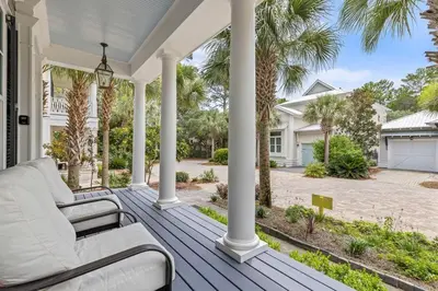 a porch with white furniture and palm trees at A Shore Bet in Santa Rosa Beach