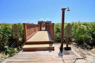a wooden walkway on the beach with two signs at 34 South Briland Main House in Rosemary Beach