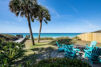 a group of blue chairs and a table on the beach at Sea Turtle Cottage in Santa Rosa Beach