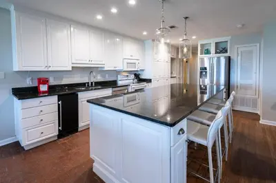 a kitchen with white cabinets and a black counter top at Sea Turtle Cottage in Santa Rosa Beach