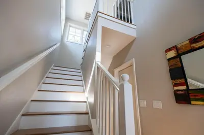 a stairway with white walls and white stairs at Sea Turtle Cottage in Santa Rosa Beach