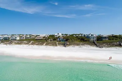 two people walking on a beach with houses in the background at Sea Turtle Cottage in Santa Rosa Beach