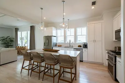 a kitchen with white cabinets and a island with bar stools at Ocho Cinco in Santa Rosa Beach