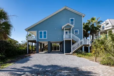 a blue house with palm trees and a driveway at 50 Sea Turtle in Santa Rosa Beach