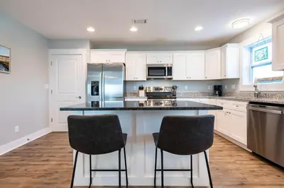 a kitchen with white cabinets and two bar stools at 50 Sea Turtle in Santa Rosa Beach