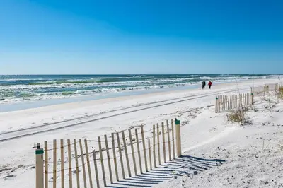 two people walking on a beach near the ocean at 50 Sea Turtle in Santa Rosa Beach