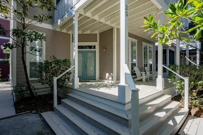 a porch of a house with a blue door and stairs at Follow the Heron in Santa Rosa Beach