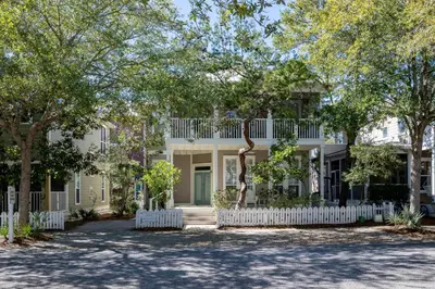 a house with a white fence and trees at Follow the Heron in Santa Rosa Beach