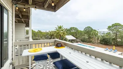 a balcony with a table and chairs and a pool at Steps to the Beach Pool Hot Tub Renovated Retreat Sea Haven by AvantStay in Santa Rosa Beach