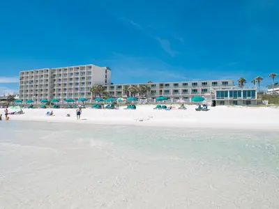 a beach with umbrellas and a hotel in the background at Beachside Resort Panama City Beach in Panama City Beach