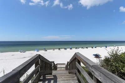 a wooden boardwalk leading to a beach with umbrellas at Grand Playa Unit 402 Gulf Front Condo in Santa Rosa Beach