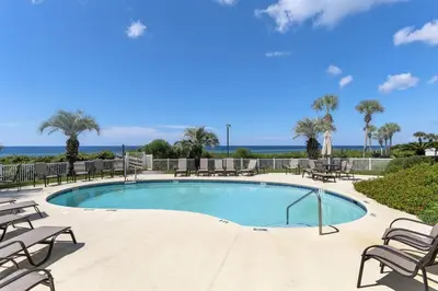 a swimming pool with tables and chairs and the ocean at Grand Playa Unit 402 Gulf Front Condo in Santa Rosa Beach