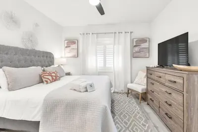 a bedroom with a bed and a tv and a dresser at Palms of Seagrove D5, Steps to the Beach, Sleeps 4, Pool, 2 bikes and 5 mins from Seaside in Seagrove Beach