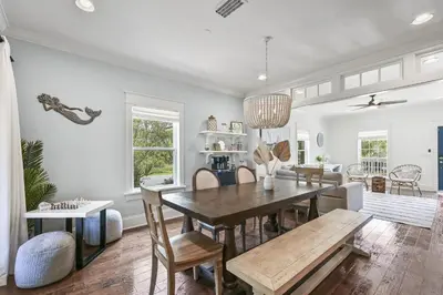 a dining room and living room with a table and chairs at Treasure Palms - Golf Cart- Bikes - Arcade- Peloton- Near Rosemary - Community Pool in Rosemary Beach