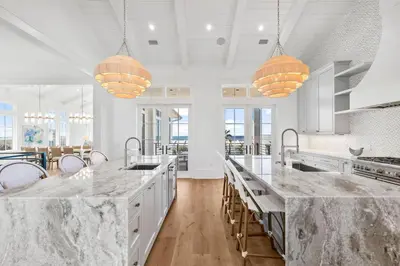a kitchen with white cabinets and marble counter tops at All Tide Up in Seacrest