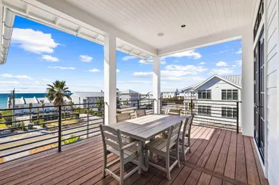 a porch with a table and chairs and the ocean at All Tide Up in Seacrest