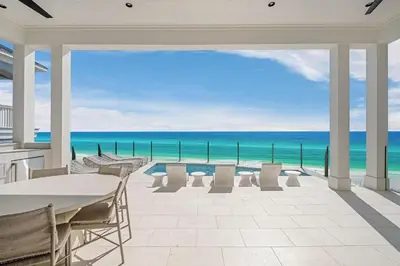 a patio with a table and chairs and the ocean at Costa Fortune in Inlet Beach