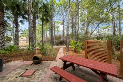 a red park bench sitting on a brick patio at 30A Beach House - The Hemingway by Panhandle Getaways in Seacrest