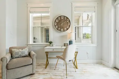 a living room with a chair and a clock on the wall at 30A Top Rated! Heated Resort Pool+Golf Cart+Bikes+Bunks+Beach Gear in Watersound Beach