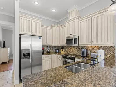 a kitchen with white cabinets and a stainless steel refrigerator at Salty Beach in Panama City Beach