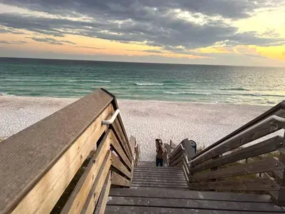 a woman walking down a wooden stairs to the beach at Beautiful Home .5mi to Beach SLPS 14! Bikes, 3rd Floor Bunk/Game Room - 2 King Bedrooms in Inlet Beach