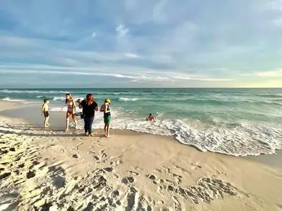 a group of people walking on the beach at Beautiful Home .5mi to Beach SLPS 14! Bikes, 3rd Floor Bunk/Game Room - 2 King Bedrooms in Inlet Beach