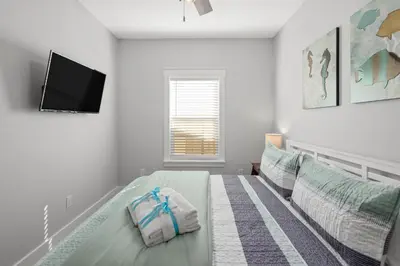 a bedroom with a bed and a flat screen tv at Laguna Haven! 3BR 2BA Sleeps 7! Your perfect escape! in Panama City Beach