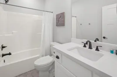 a white bathroom with a toilet and a sink at Laguna Haven! 3BR 2BA Sleeps 7! Your perfect escape! in Panama City Beach