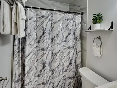 a white marble shower curtain in a bathroom at Seashell Cottage in Panama City Beach