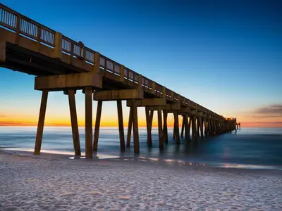 a wooden pier on the beach at sunset at Seashell Cottage in Panama City Beach