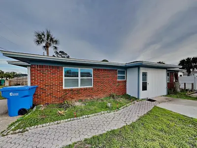 a brick house with a blue trash can in front of it at Seashell Cottage in Panama City Beach