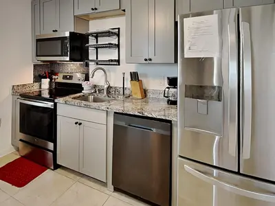 a kitchen with white cabinets and a stainless steel refrigerator at Seashell Cottage in Panama City Beach