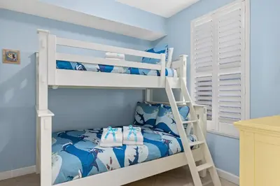 a bunk bed in a blue room with a bunk bed at Grandview Oasis! 3BR 2BA Sleeps 9! Gulf-front tranquility beckons! in Panama City Beach