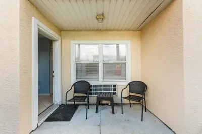 two chairs and a table on a porch with a window at Merrimac Resort #43 in Panama City Beach