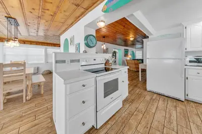 a kitchen with white appliances and a dining room at If Its The Beaches by Emerald Coast Retreats in Panama City Beach