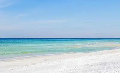 a group of people walking on the beach at If Its The Beaches by Emerald Coast Retreats in Panama City Beach