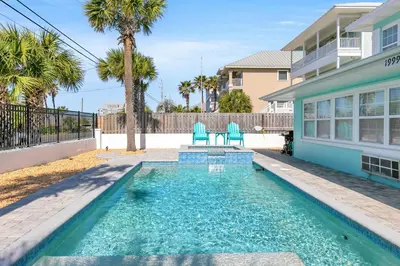 a swimming pool with two blue chairs in front of a house at If Its The Beaches by Emerald Coast Retreats in Panama City Beach