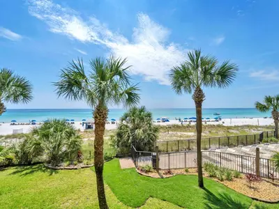 a view of the beach from the balcony of a resort with palm trees at Commodore 203 in Panama City Beach