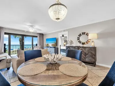 a dining room and living room with a table and chairs at Commodore 203 in Panama City Beach