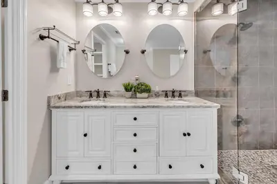 a white bathroom with two sinks and two mirrors at Sterling Beach #301 in Panama City Beach