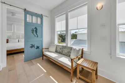 a living room with a couch and a bed and windows at Just Breezin' in Santa Rosa Beach