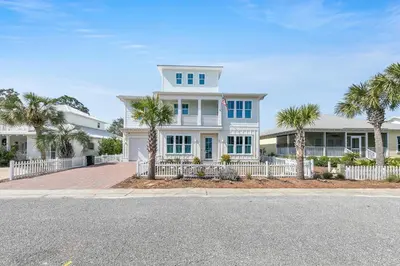 a white house with palm trees in front of it at Just Breezin' in Santa Rosa Beach