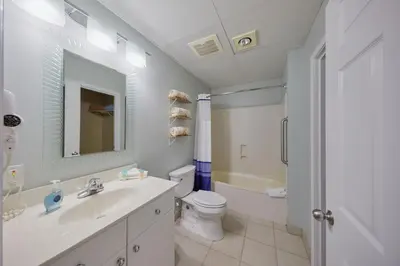 a white bathroom with a sink and a toilet at Palmetto Beachfront Hotel, a By The Sea Resort in Panama City Beach
