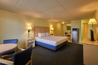 a hotel room with a bed and a table and chairs at Palmetto Beachfront Hotel, a By The Sea Resort in Panama City Beach