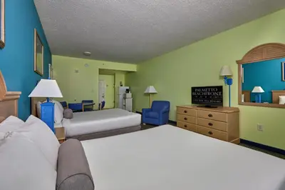 a hotel room with two beds and a tv at Palmetto Beachfront Hotel, a By The Sea Resort in Panama City Beach